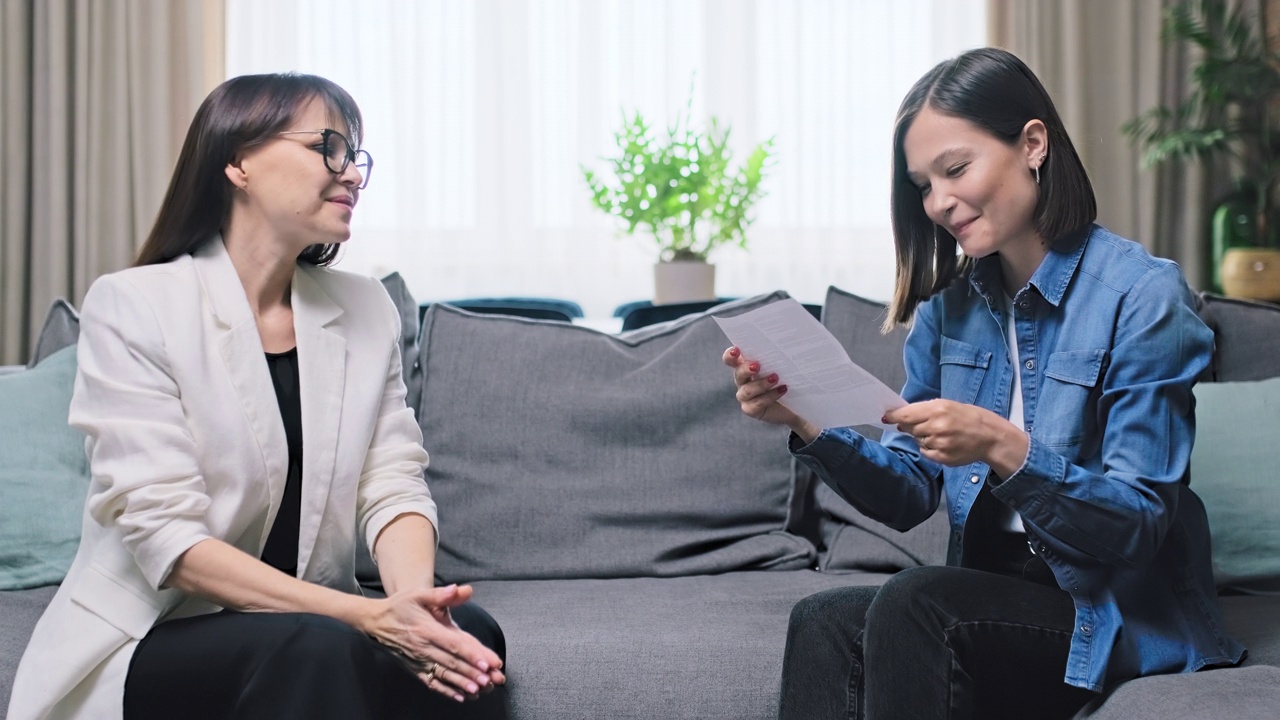 成熟的商业女性给年轻女性递上一封好消息信