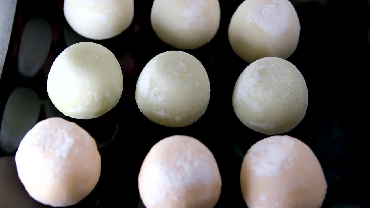 麻糬冰淇淋咬一口甜点，然后把它放回一个带有绿茶味的黑色盘子里，这是一种受欢迎的亚洲美食