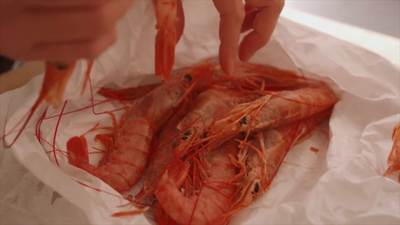一名妇女剥虾皮做Gambas al ajillo(西班牙大蒜辣椒虾)