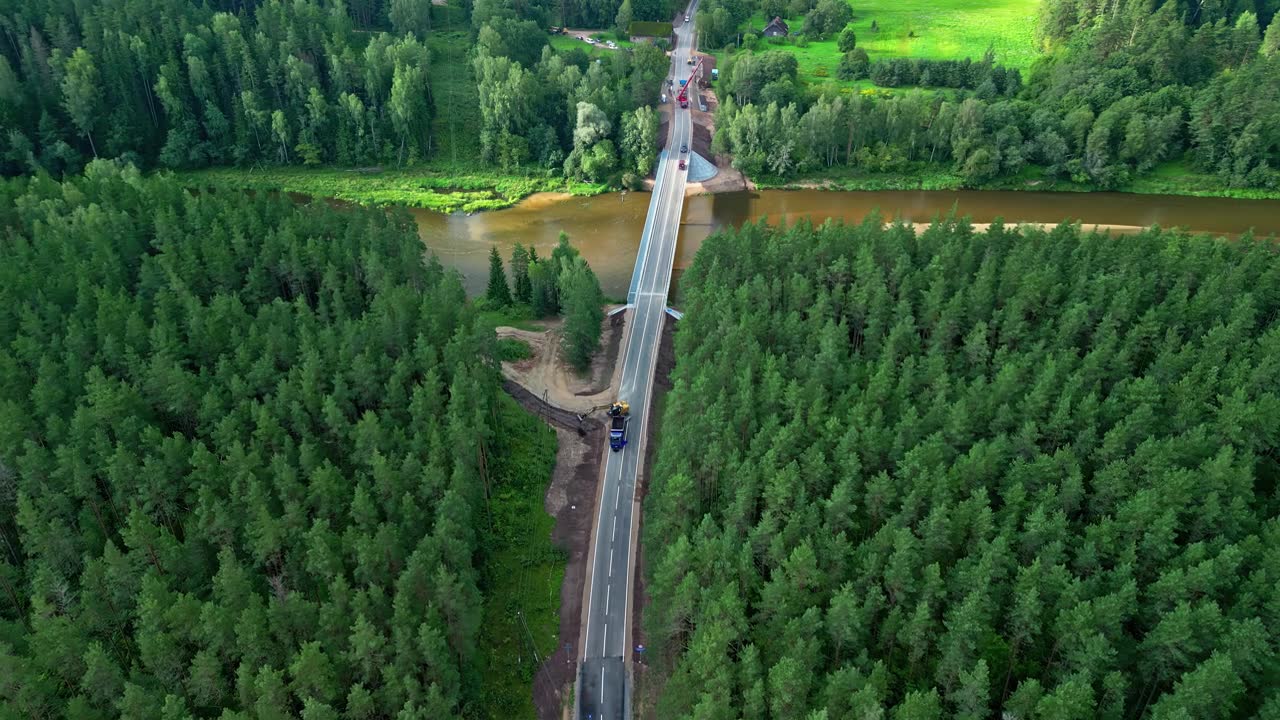 詳情圖-從拉脫維亞的無人機(jī)拍攝的綠色森林和棕色渾濁河流之間正在建設(shè)的道路。