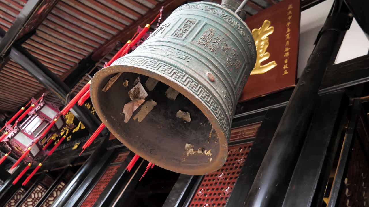 中国成都文殊寺屋顶下悬挂的大铜钟。这个古老而雄伟的钟，装饰着复杂的细节和象征性的雕刻，散发着一种灵性感。