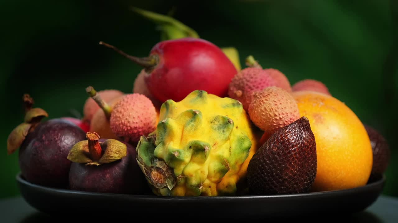 在绿色背景上旋转异国水果(百香果，柽柳，荔枝，Pitahaya, Salak, Granadilla，山竹)
