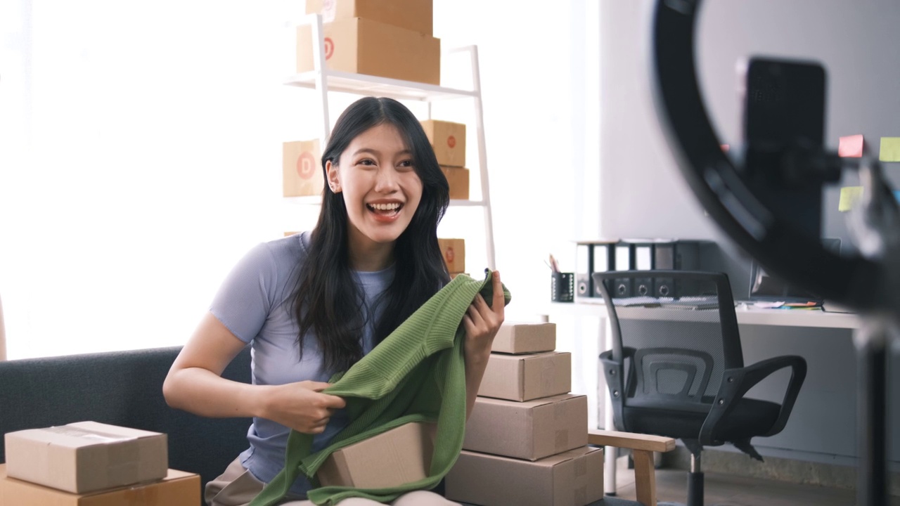 詳情圖-熱情的亞洲企業(yè)主，服裝或布料在線商店與她的客戶在線互動，直播以吸引更多的客戶關(guān)注。