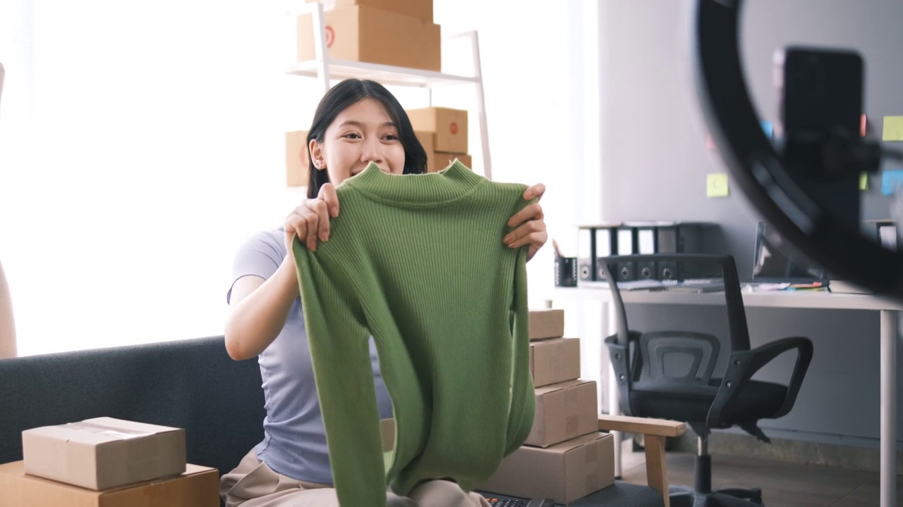 詳情圖-熱情的亞洲企業(yè)主，服裝或布料在線商店與她的客戶在線互動，直播以吸引更多的客戶關(guān)注。
