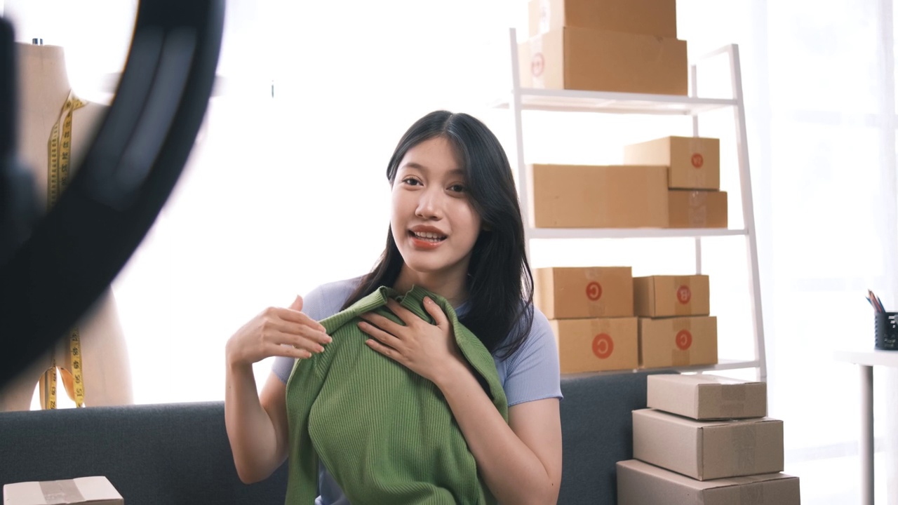 詳情圖-熱情的亞洲企業(yè)主，服裝或布料在線(xiàn)商店與她的客戶(hù)在線(xiàn)互動(dòng)，直播以吸引更多的客戶(hù)關(guān)注。
