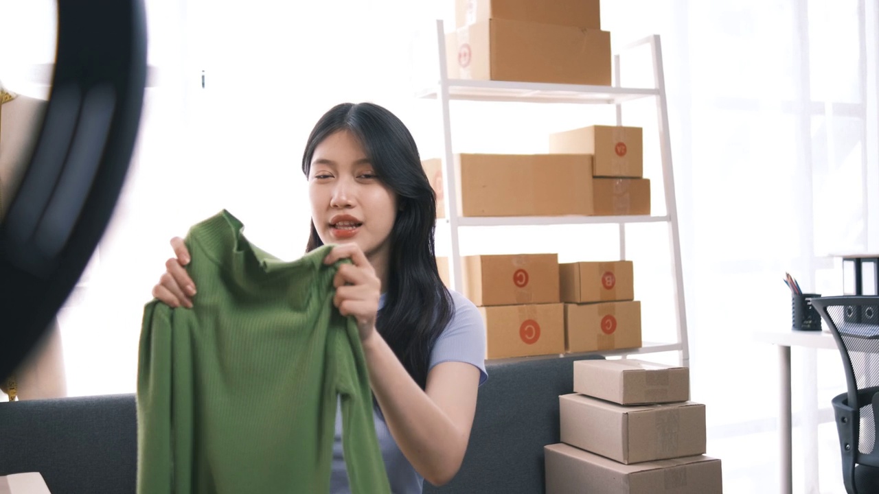 詳情圖-熱情的亞洲企業(yè)主，服裝或布料在線(xiàn)商店與她的客戶(hù)在線(xiàn)互動(dòng)，直播以吸引更多的客戶(hù)關(guān)注。
