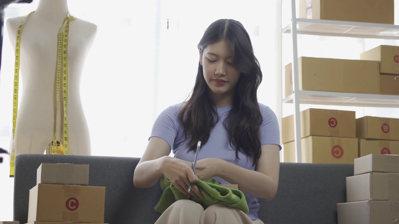 详情图-亚洲女孩在公寓用笔记本电脑在网上卖衣服，时尚博主在网上博客录视频，可爱的女人在家里的网上服装店直播