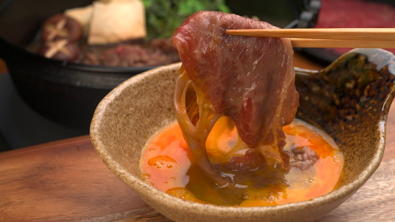 将寿喜烧肉浸在打好的鸡蛋中食用