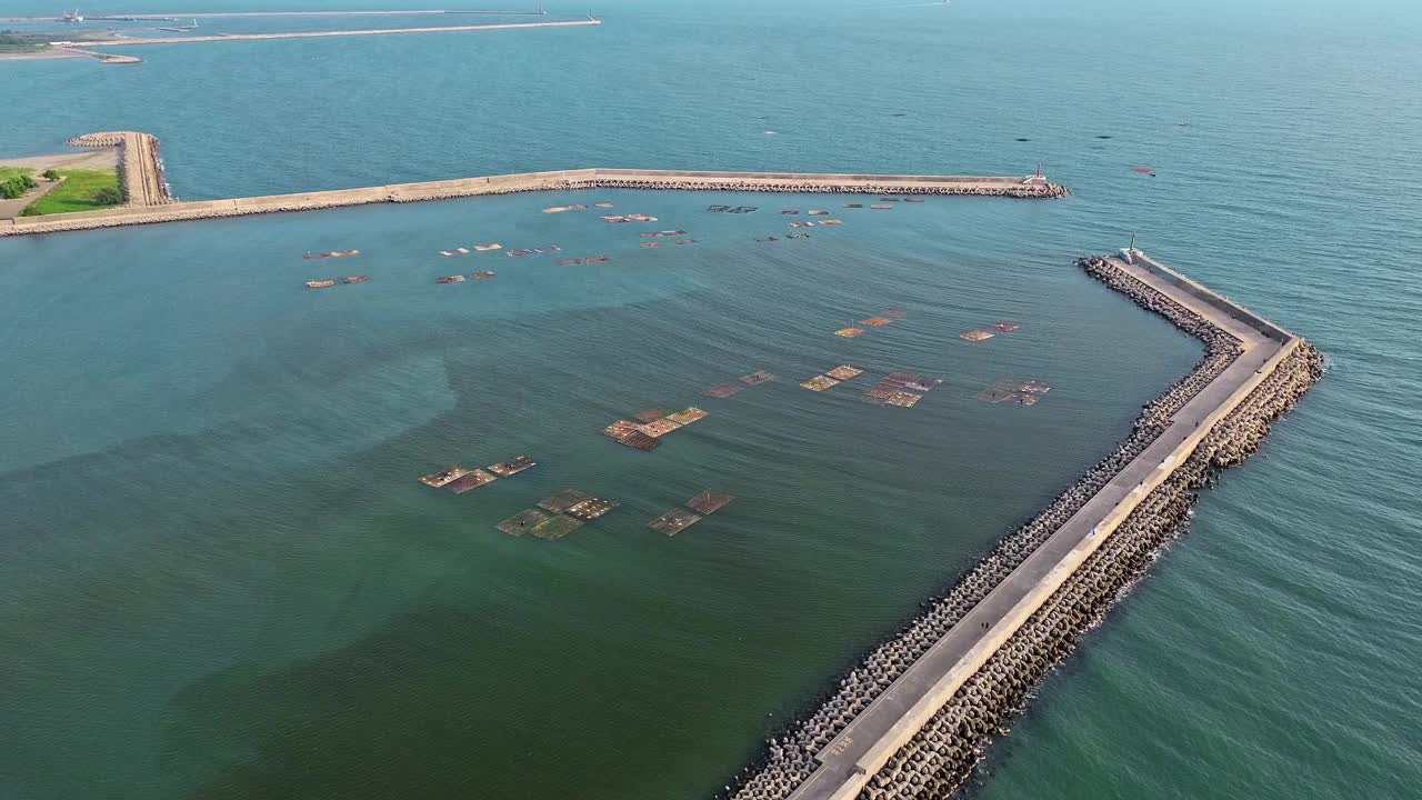在台湾南部的台南屿光岛，航拍4k的破浪块和养殖牡蛎的木筏。这是一个受游客欢迎的海滩。