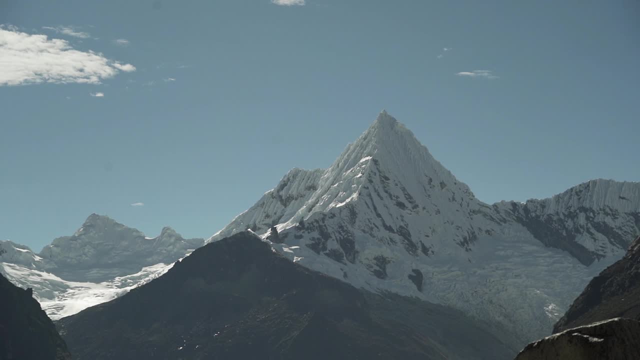 在秘鲁华斯卡兰的白科迪勒拉安第斯山脉的高山上，拉古纳帕隆泻湖的一座金字塔形山的冰川被冰雪覆盖，阳光明媚的日子里，山峰被白雪覆盖。