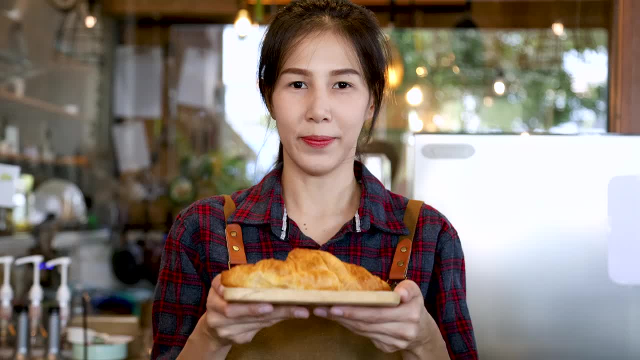 4k，生活方式快乐的面包店老板提供美味的羊角面包盘，亚洲女性站在镜头前，小企业创业聘请有吸引力的模特女孩直播自制面包店
