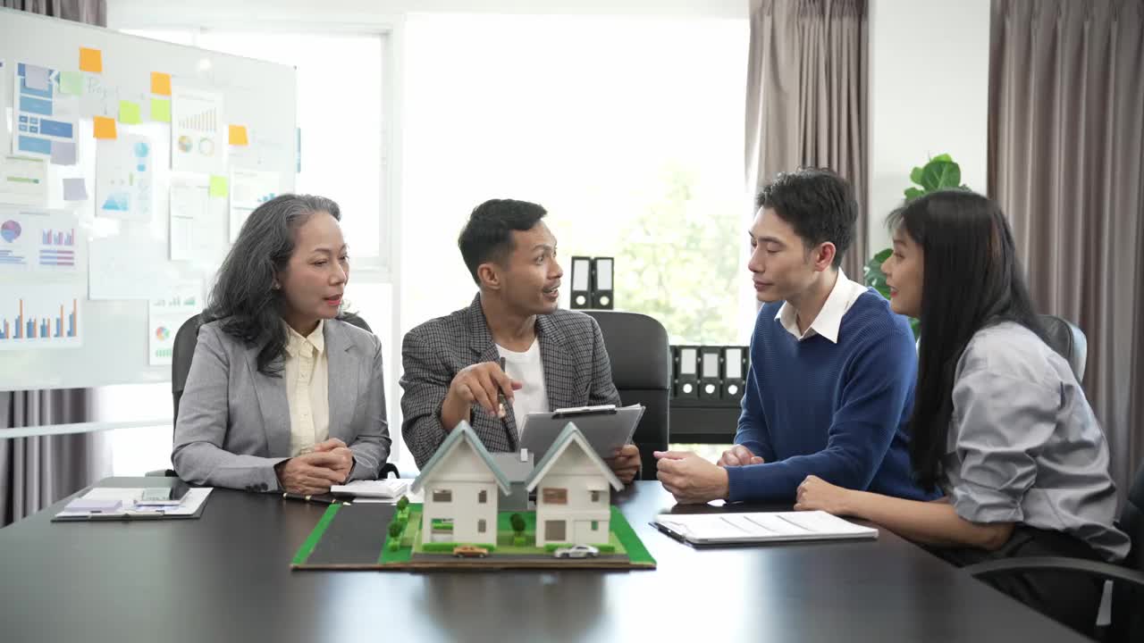 房地产经纪人正在讲解房屋模型查看房屋平面图和买卖合同，房屋买卖合同的条件，与客户合法签订合同。