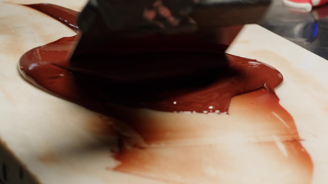 女厨师糖果师制作巧克力糖果，为慕斯粉蛋糕倒可可，奶油甜点特写美食艺术。餐厅甜品，白糖甜品，杏仁巧克力慕斯。