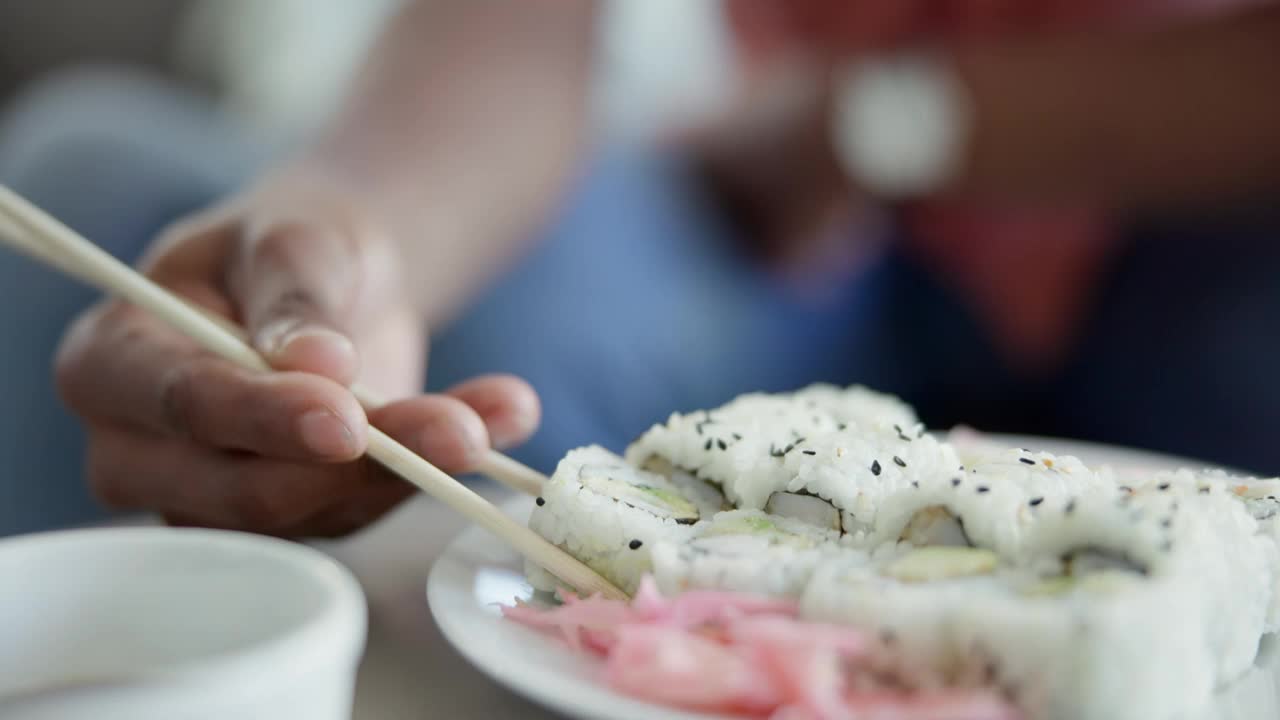 餐厅，午餐手拿寿司吃，特写食物和营养搭配海鲜。餐盘、餐筷与人搭配，适合亚洲美食、日本美食或日本文化大餐