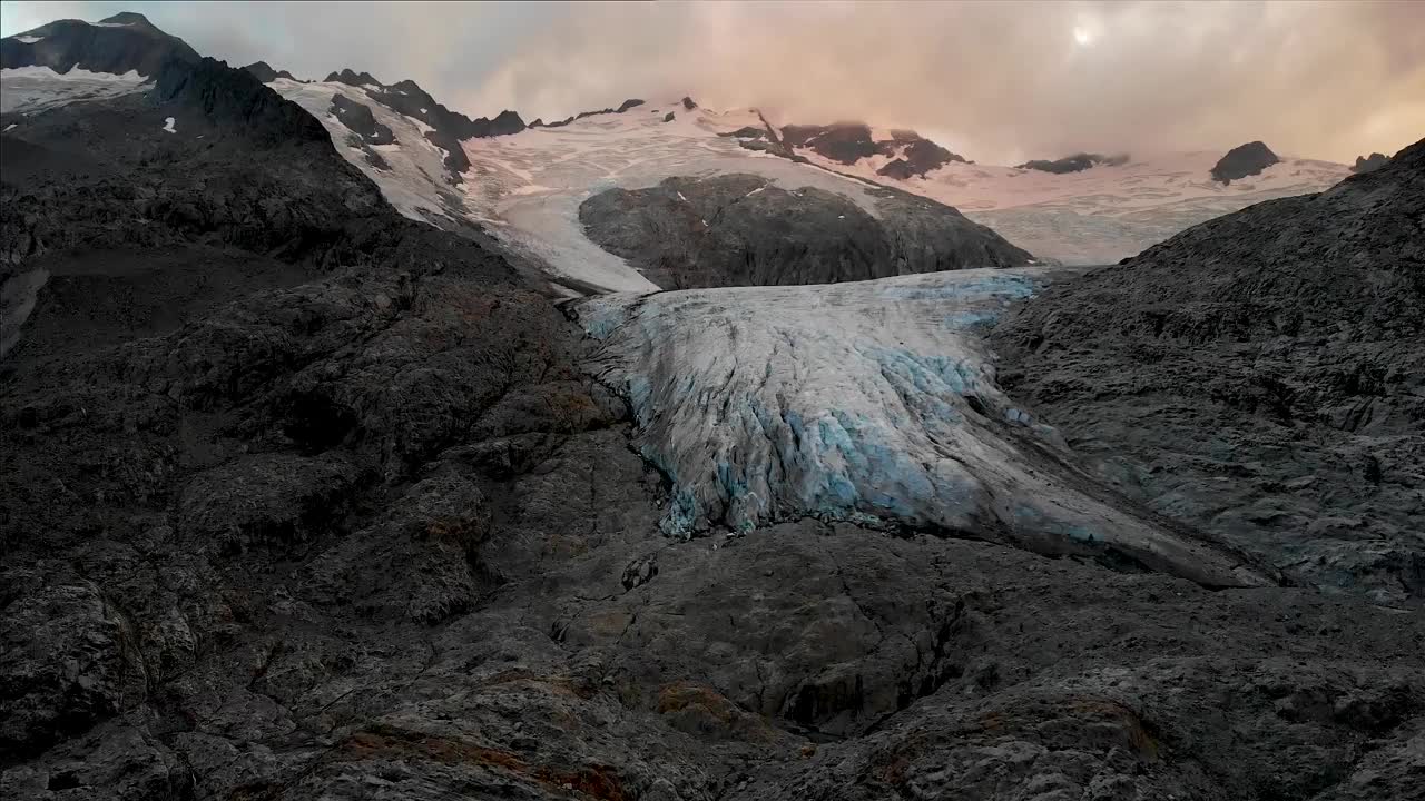 从瑞士阿尔卑斯山伯尔尼高地地区的高利冰川的近景开始，在多云的日子里，太阳落山。