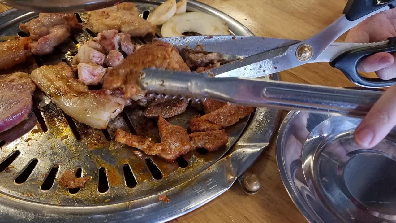 在韩国餐厅吃烧烤。熏肉，五花肉，牛肉在木炭烤架上烤。