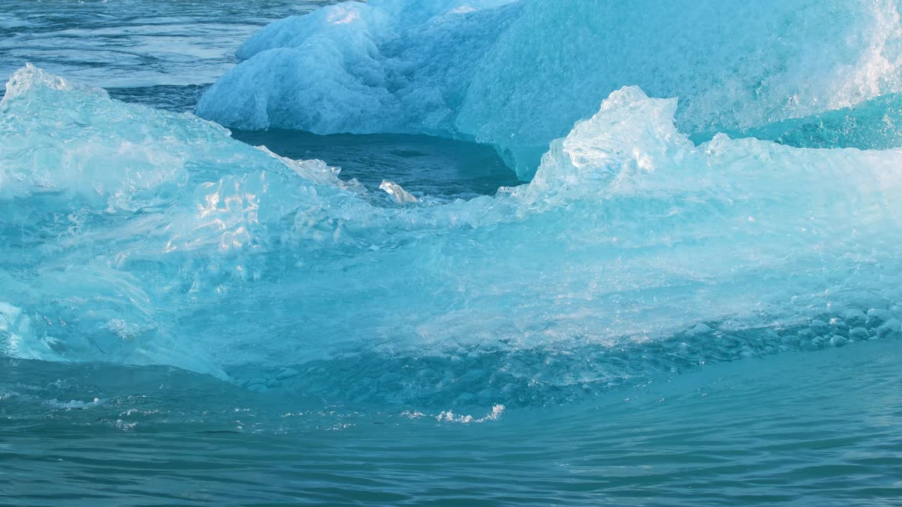 蓝色冰山在咸水中漂流，冰岛的Jokulsarlon冰川泻湖，冰川融化产生的纯蓝色冰