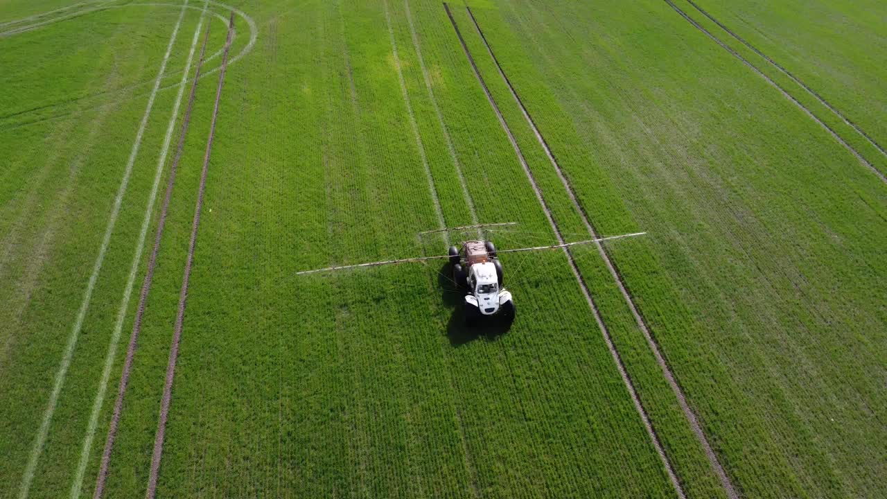 一輛特殊的拖拉機在一片綠地上噴灑農(nóng)藥。農(nóng)民在麥田里噴灑除草劑。農(nóng)業(yè)機械加工大豆作物。從上面看。農(nóng)業(yè)的概念