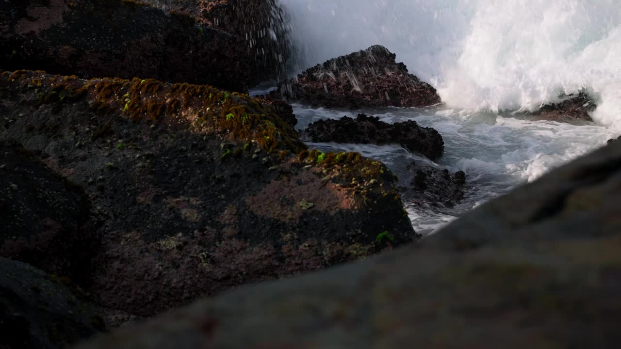 汹涌的海浪拍打着崎岖的海岸线岩石。海水喷溅，大海怒吼，海岸风光自然光。动态海景捕捉大自然的力量在阳光明媚的日子。