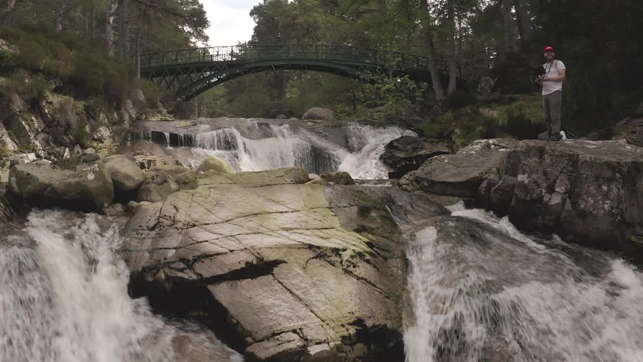 空中回拉拍摄的河流和Garbh Allt瀑布桥在气球森林，在苏格兰，英国的野生自然