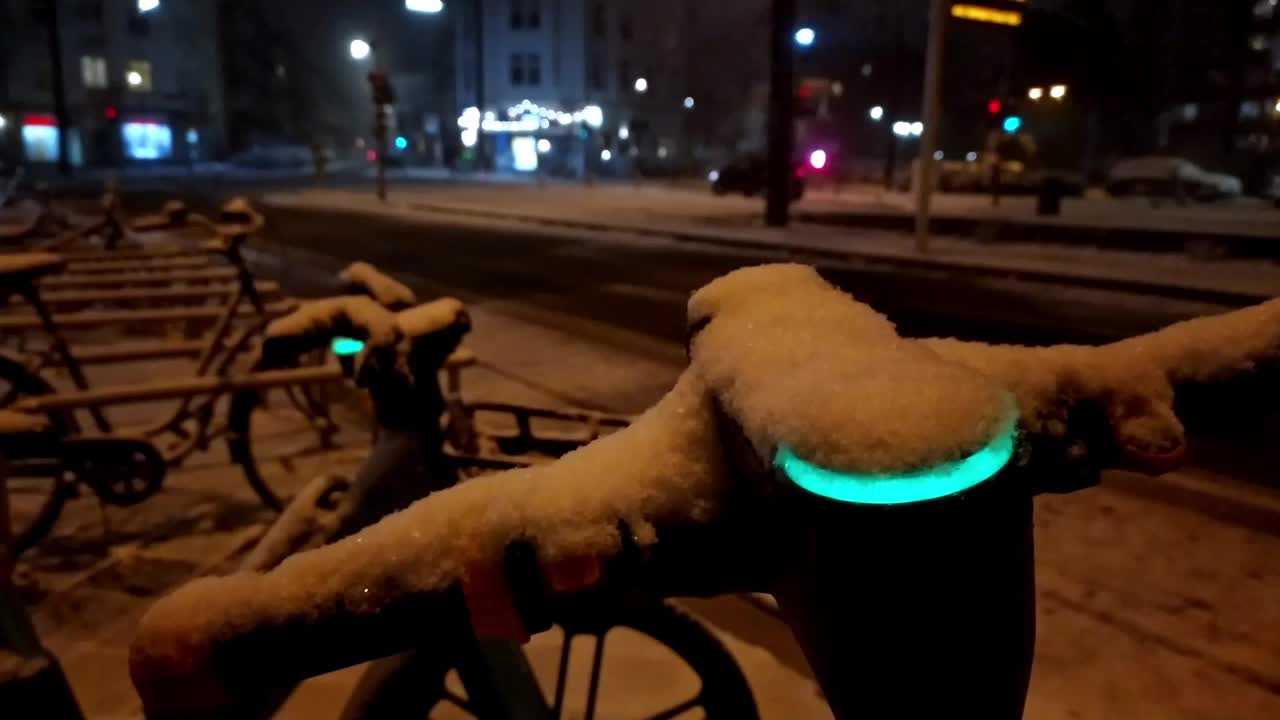 雪天的冬夜，在雪天的城市街道上使用电动滑板车或机动自行车共享概念，展示了像电动汽车一样在现代城市生活安全中的环保交通方式