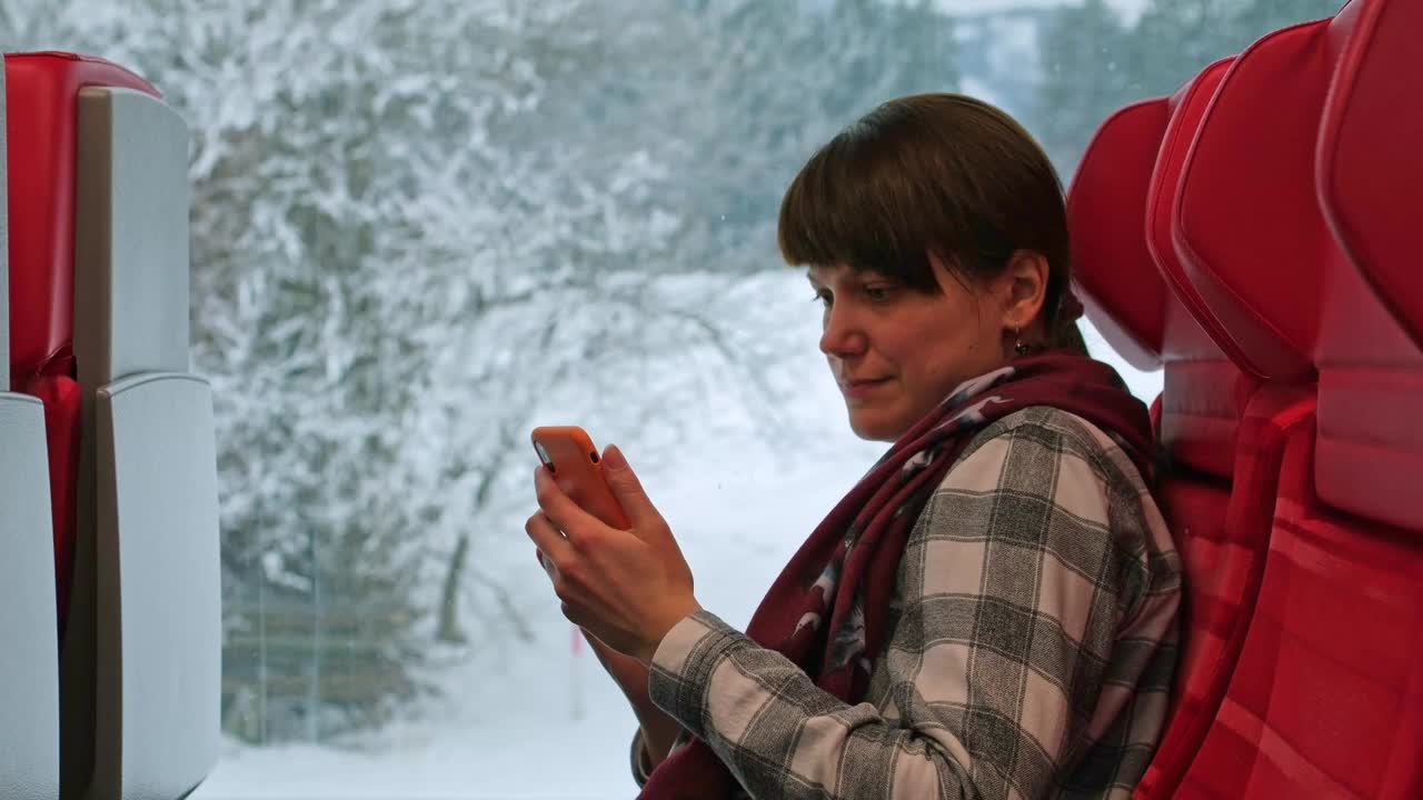 一名女子对着窗外的雪景自拍