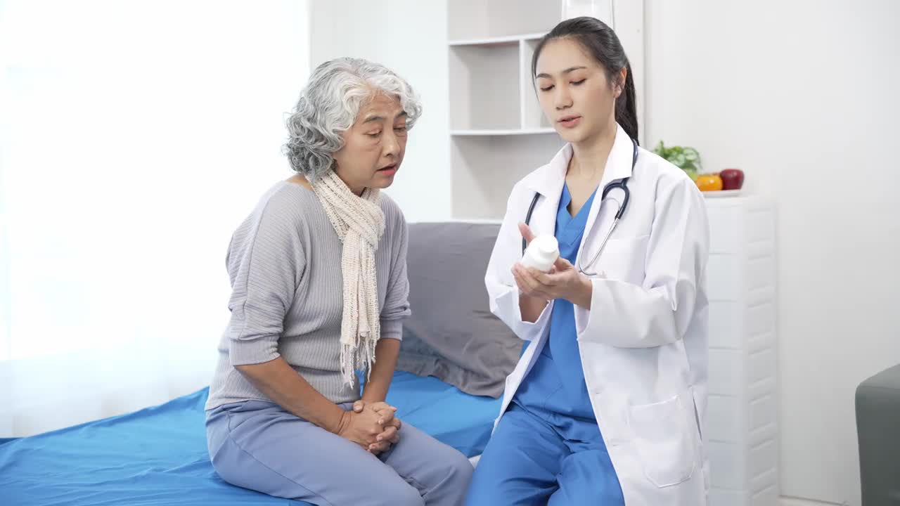 亚洲护理护士在病床上检查老年亚洲女病人。有吸引力的照顾者支持，提供建议和咨询与老年祖母在诊所。4 k 60 p
