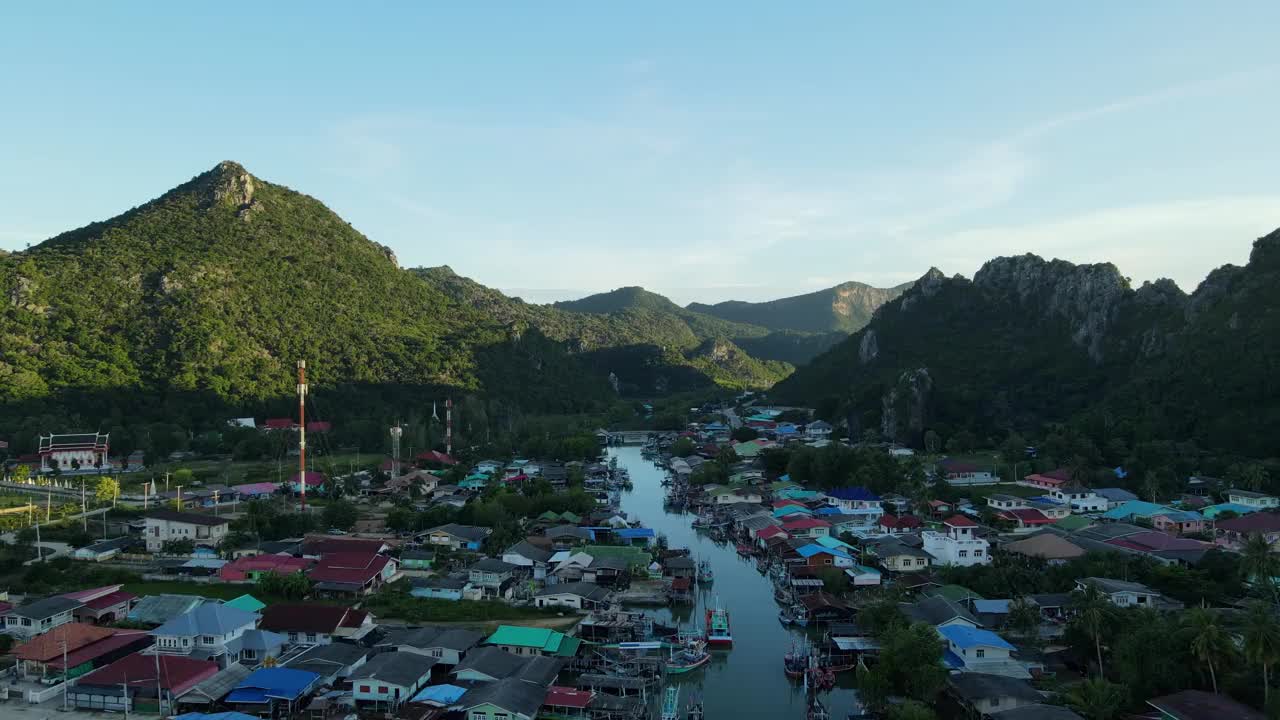 无人机飞向风景如画的风景，而Bang Pu渔村被山脉的阴影所覆盖，泰国，Prachuap Khiri Khan, Sam Roi Yot国家公园。