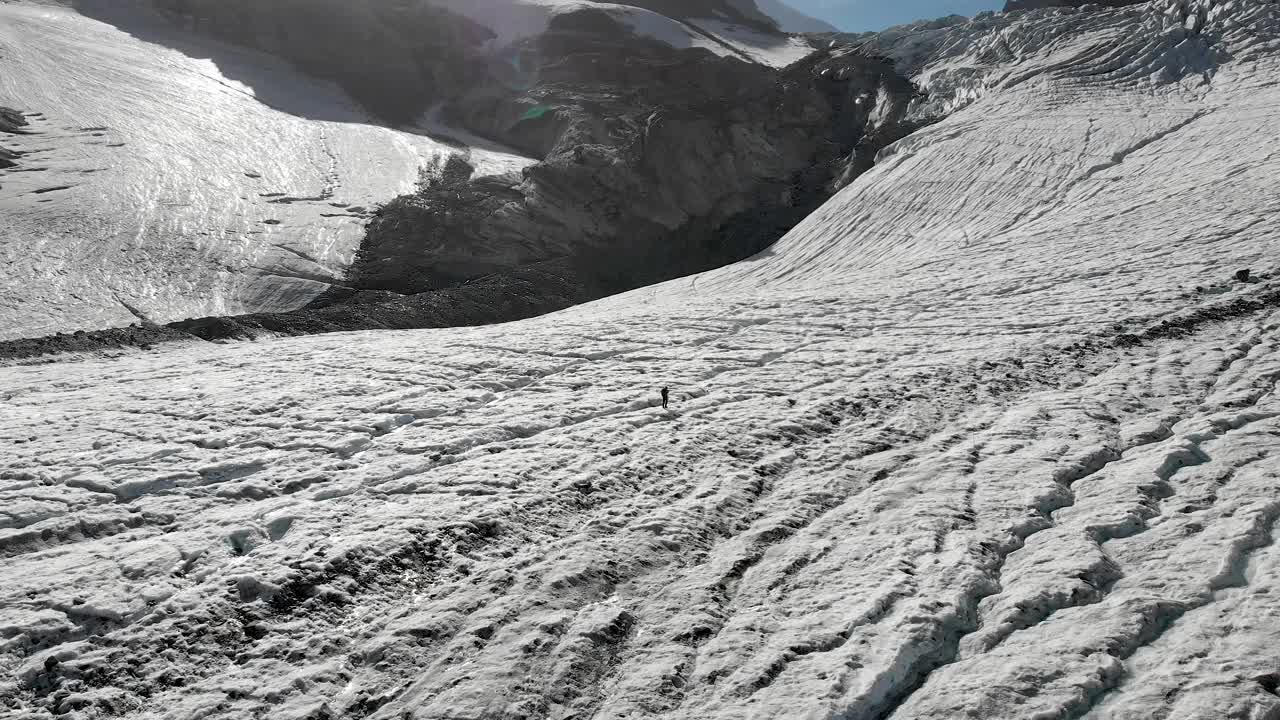 在瑞士阿尔卑斯山阳光明媚的一天，徒步旅行者在瑞士瓦莱州萨斯费附近的Allalin冰川上行走的鸟瞰图