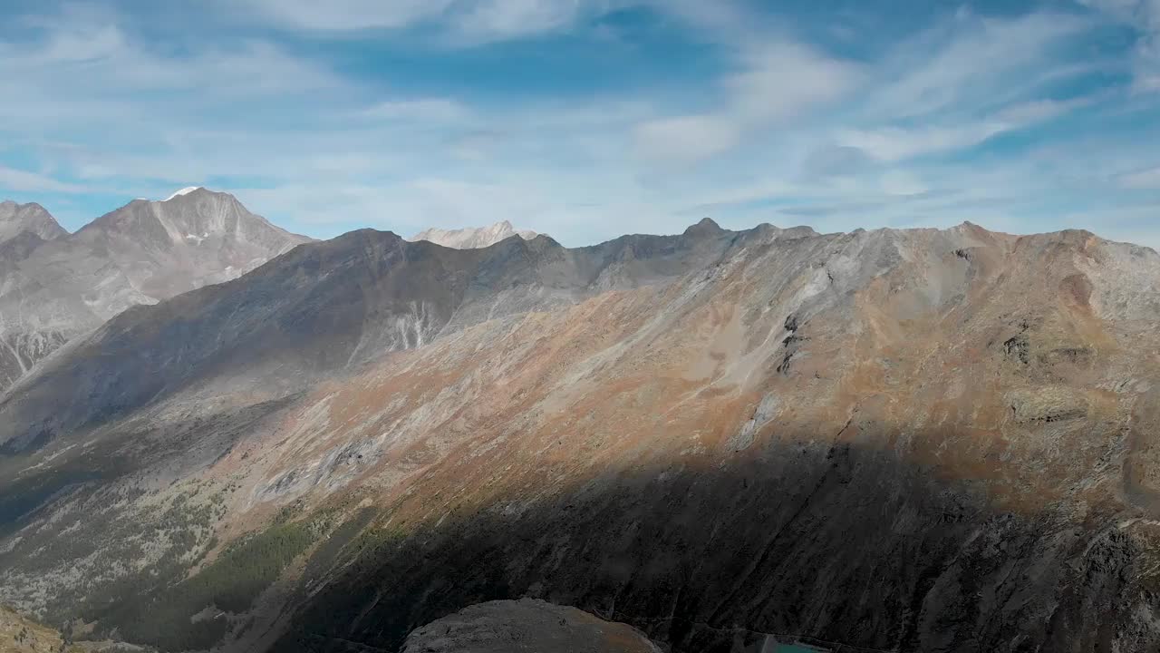 在瑞士瓦莱州萨斯费附近，一个阳光明媚的夏日，在瑞士阿尔卑斯山，一名徒步旅行者俯瞰Allalin和Hohlaub冰川，Allalinhorn峰和Mattmarksee在视野中。