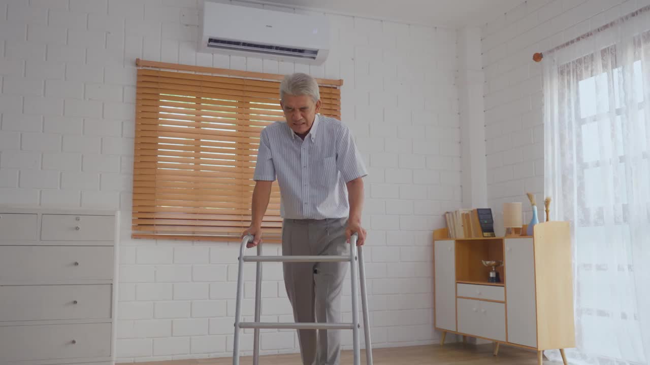亚洲护理员在家中帮助老年男性避免摔倒。老年患者在进行物理治疗后发生事故，然后在客厅被有吸引力的治疗师护士救出。