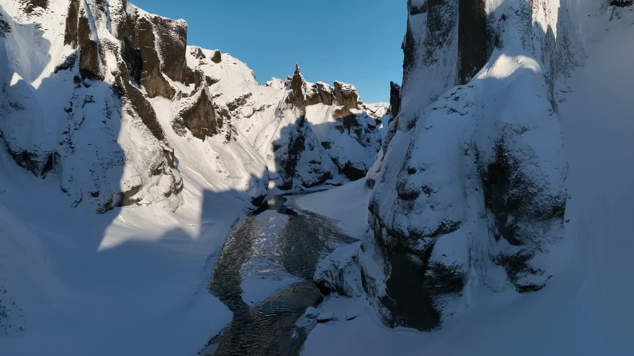 在一个阳光明媚的日子里，鸟瞰覆盖着雪的峡谷，俯瞰冰川河流