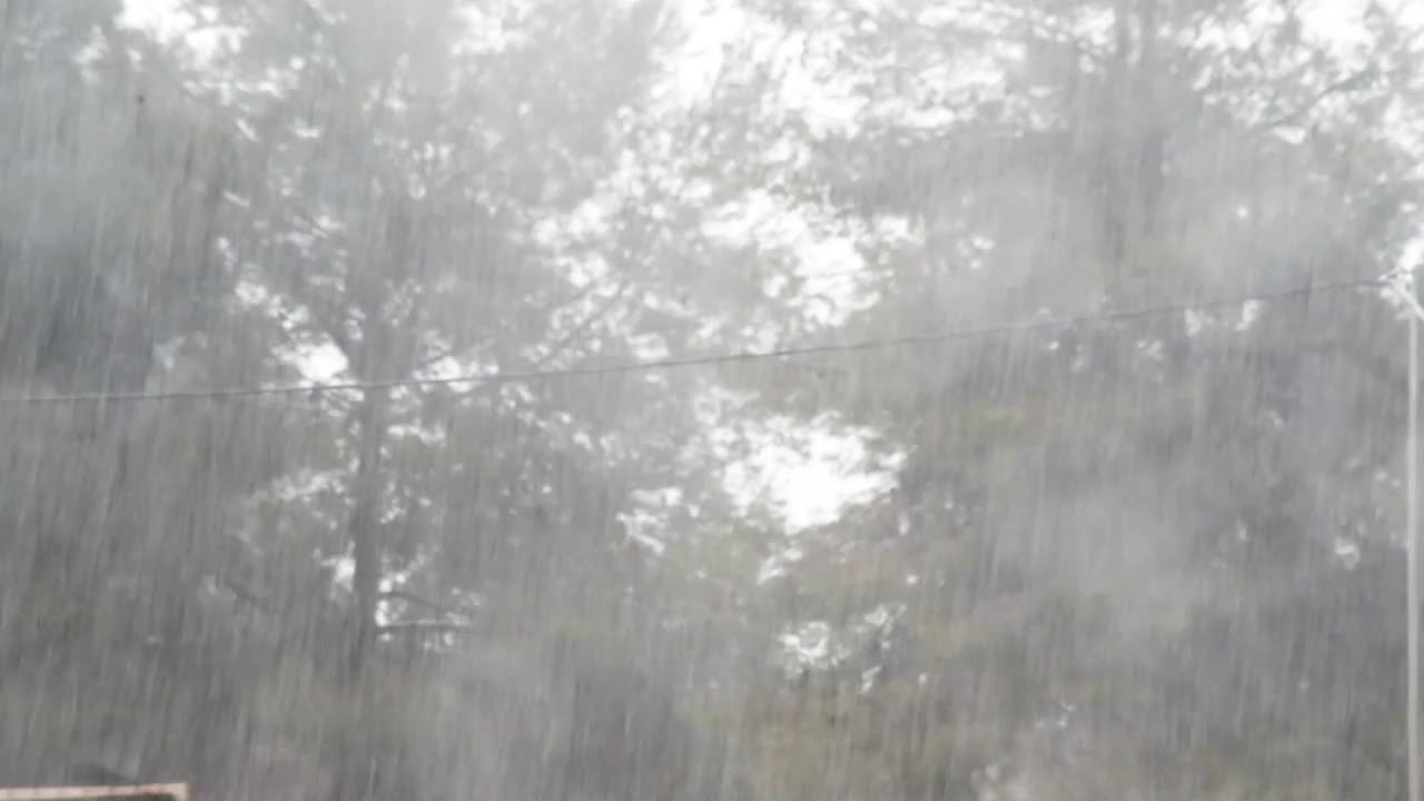 背景是倾盆大雨，透过玻璃窗拍摄，选择性聚焦。下雨天从天上流下的溪水。台风期间恶劣阴沉的天气背景。概念的灾难。