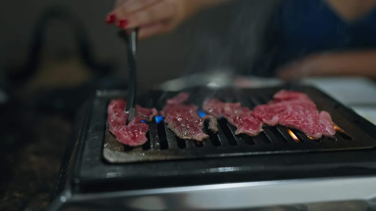 现代用餐体验，年轻女子的手煮美味，罕见的和牛在日本餐厅烧烤，品尝多汁的烤肉