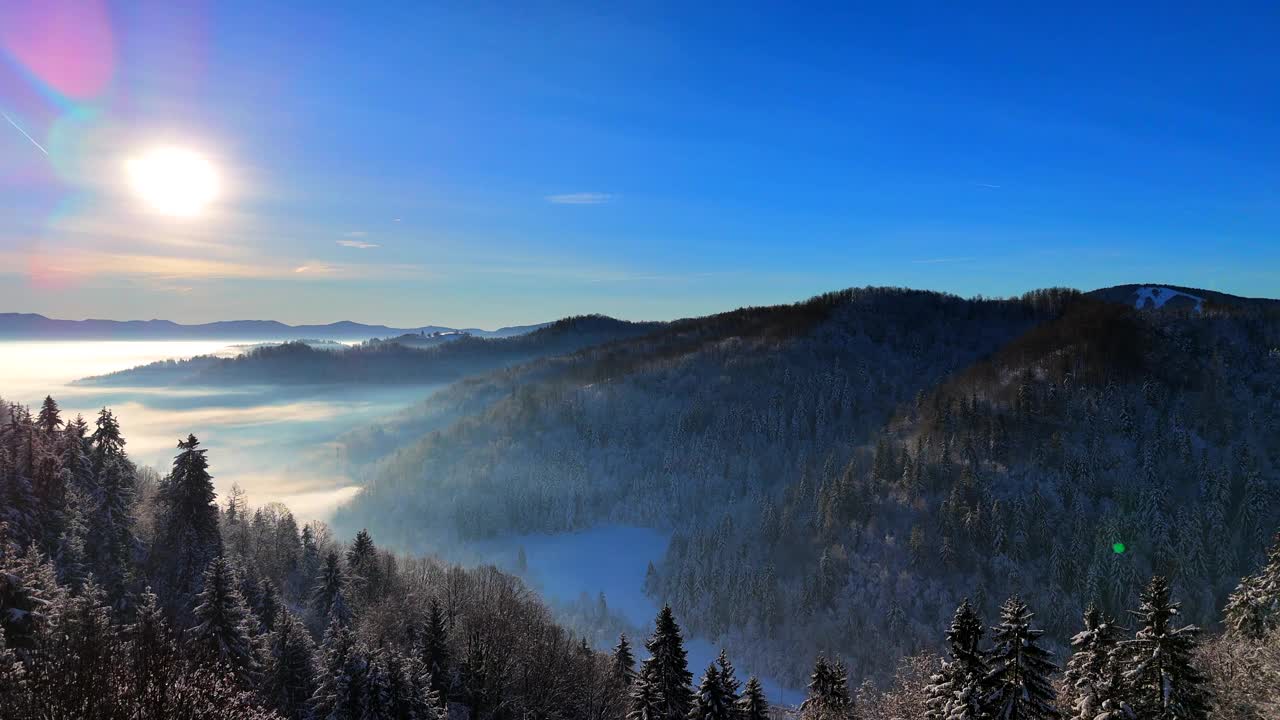 冬日里一个阳光明媚的日子里，白雪覆盖的森林和雾气弥漫的山谷上空