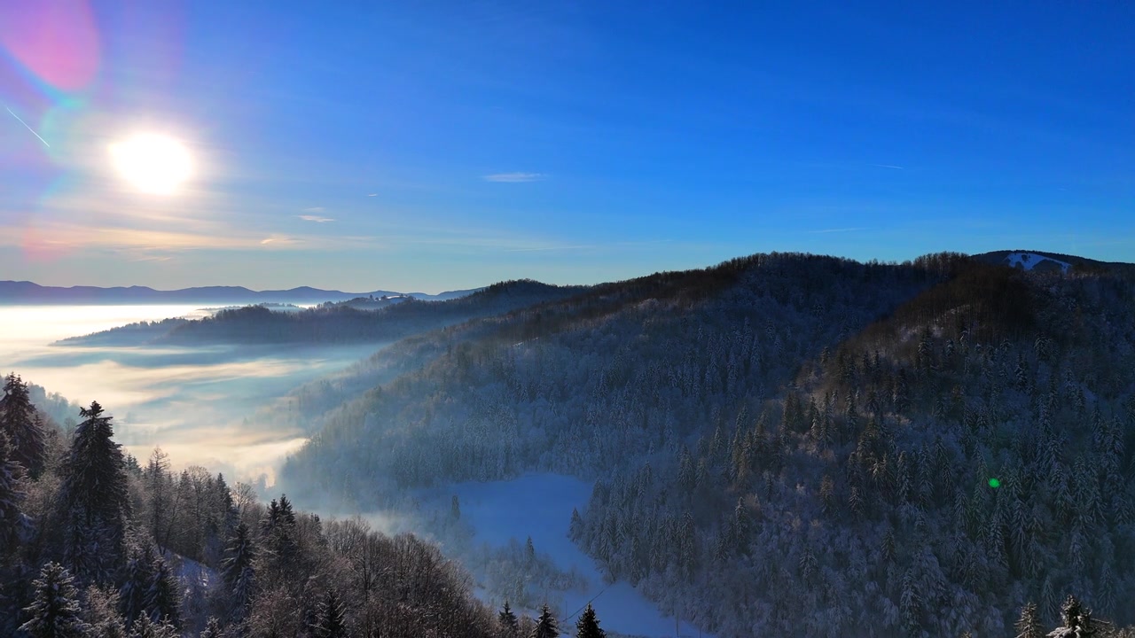 詳情圖-冬日里一個陽光明媚的日子里，白雪覆蓋的森林和霧氣彌漫的山谷上空