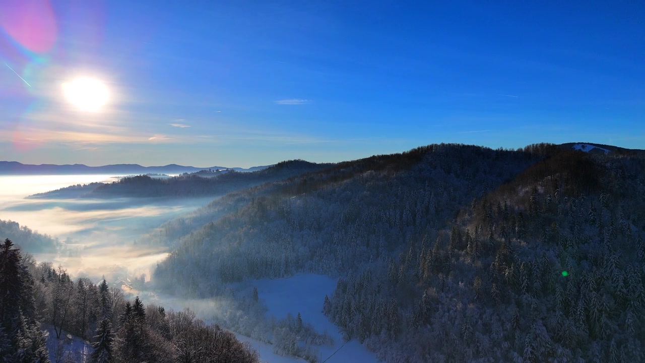 詳情圖-冬日里一個陽光明媚的日子里，白雪覆蓋的森林和霧氣彌漫的山谷上空