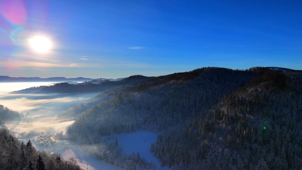 詳情圖-冬日里一個陽光明媚的日子里，白雪覆蓋的森林和霧氣彌漫的山谷上空