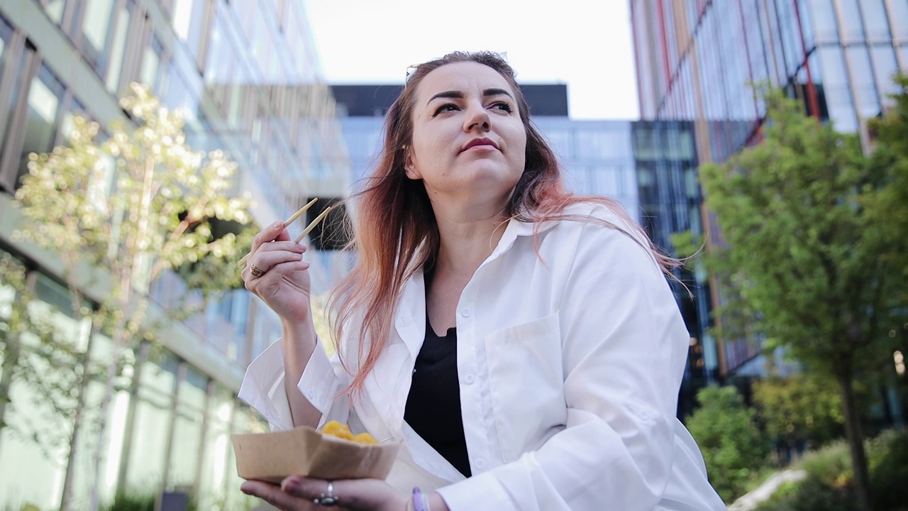一位成年妇女在外面享用午餐。上班族用筷子吃饺子