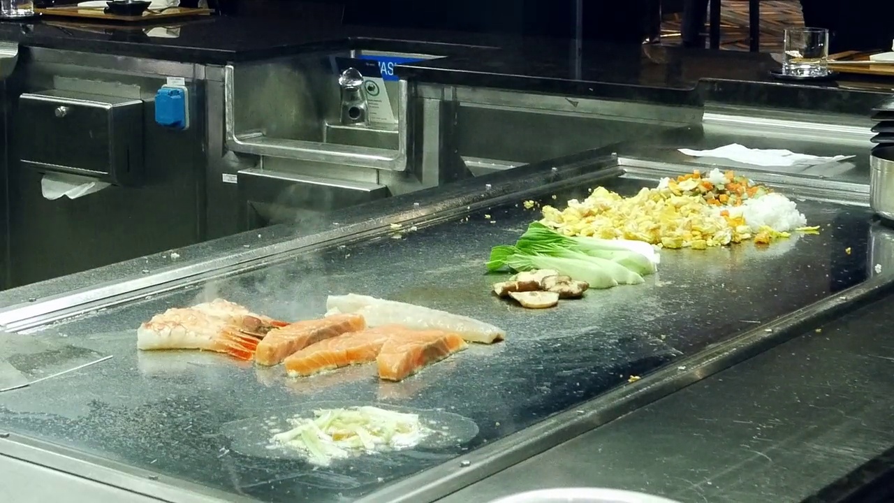 不知名的厨师在燃烧的烤架上烹饪美味的铁板烧的延时特写