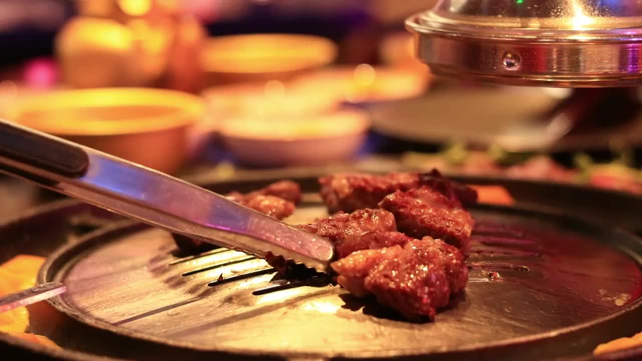 在韩国餐厅煮牛肉，把肉翻过来煮，特写