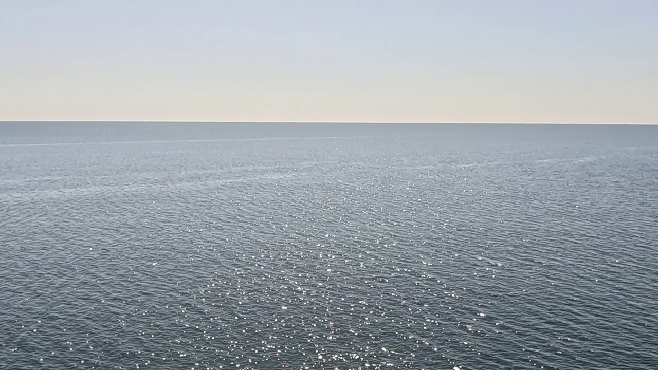 海水表面。鸟瞰清澈湛蓝的海水。太阳眩光。抽象航海夏季海洋自然。度假、度假、旅游的概念。没有人。缓慢的运动。天气和气候变化