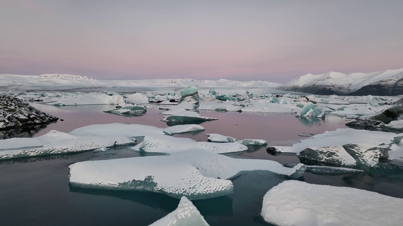 在冰岛南部粉色日落期间，在Jökulsárlón冰川泻湖上空飞行-无人机拍摄