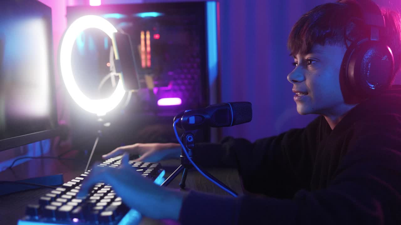 流玩家玩電子競技視頻游戲在線比賽。小男孩在游戲室內(nèi)與團隊成員聊天