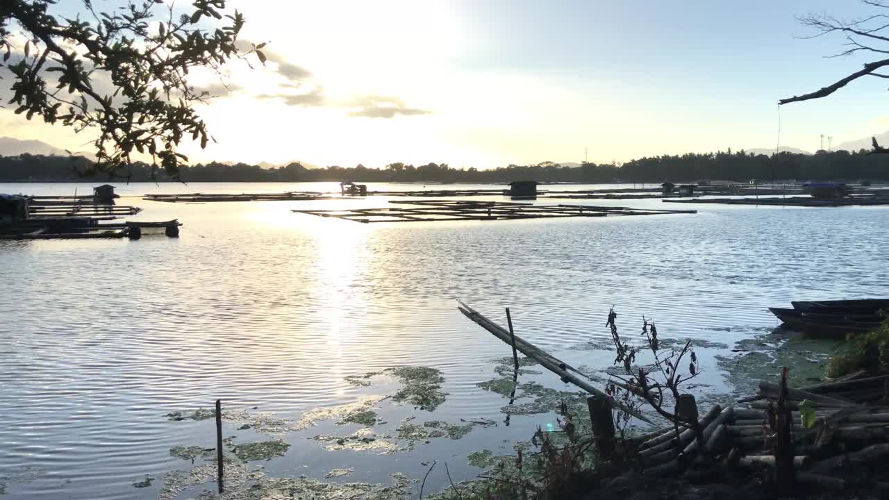 湖上漂浮的鱼笼，被夕阳金色的阳光照亮。轮廓