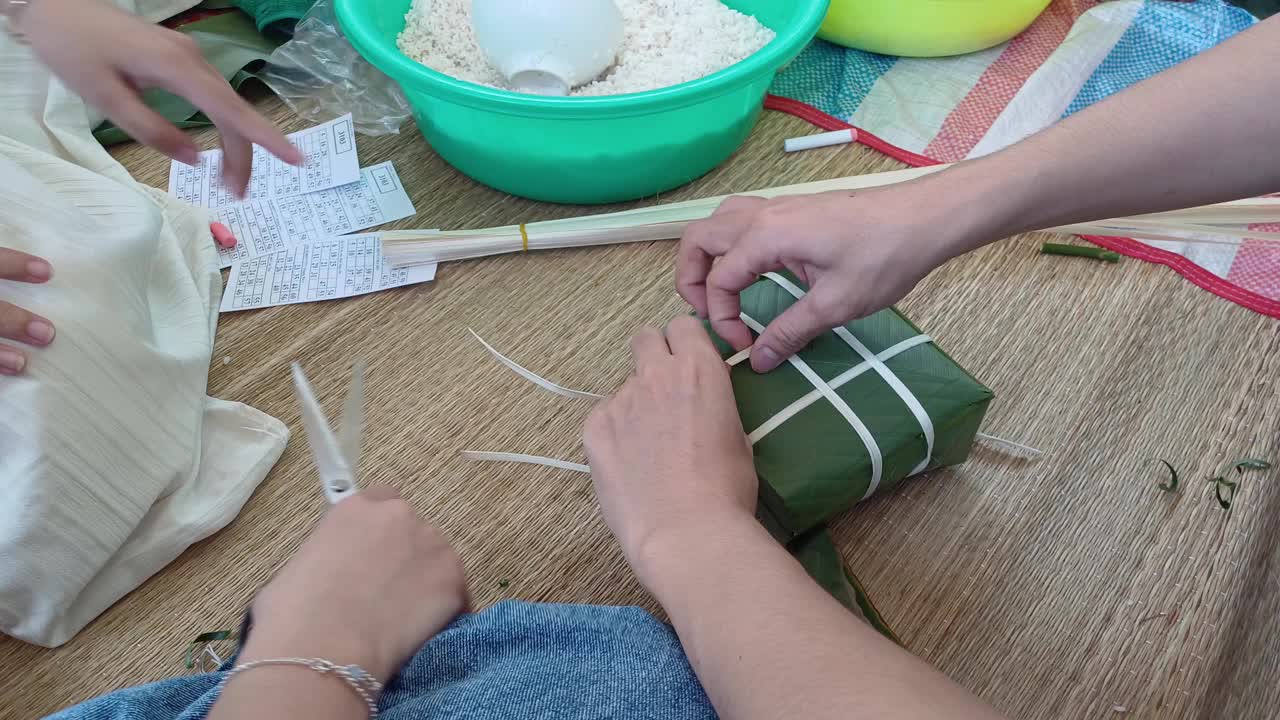 手正在包粽子或糯米糕，这是越南的传统食品，用猪肉、绿豆、糯米裹上绿叶，然后煮熟。