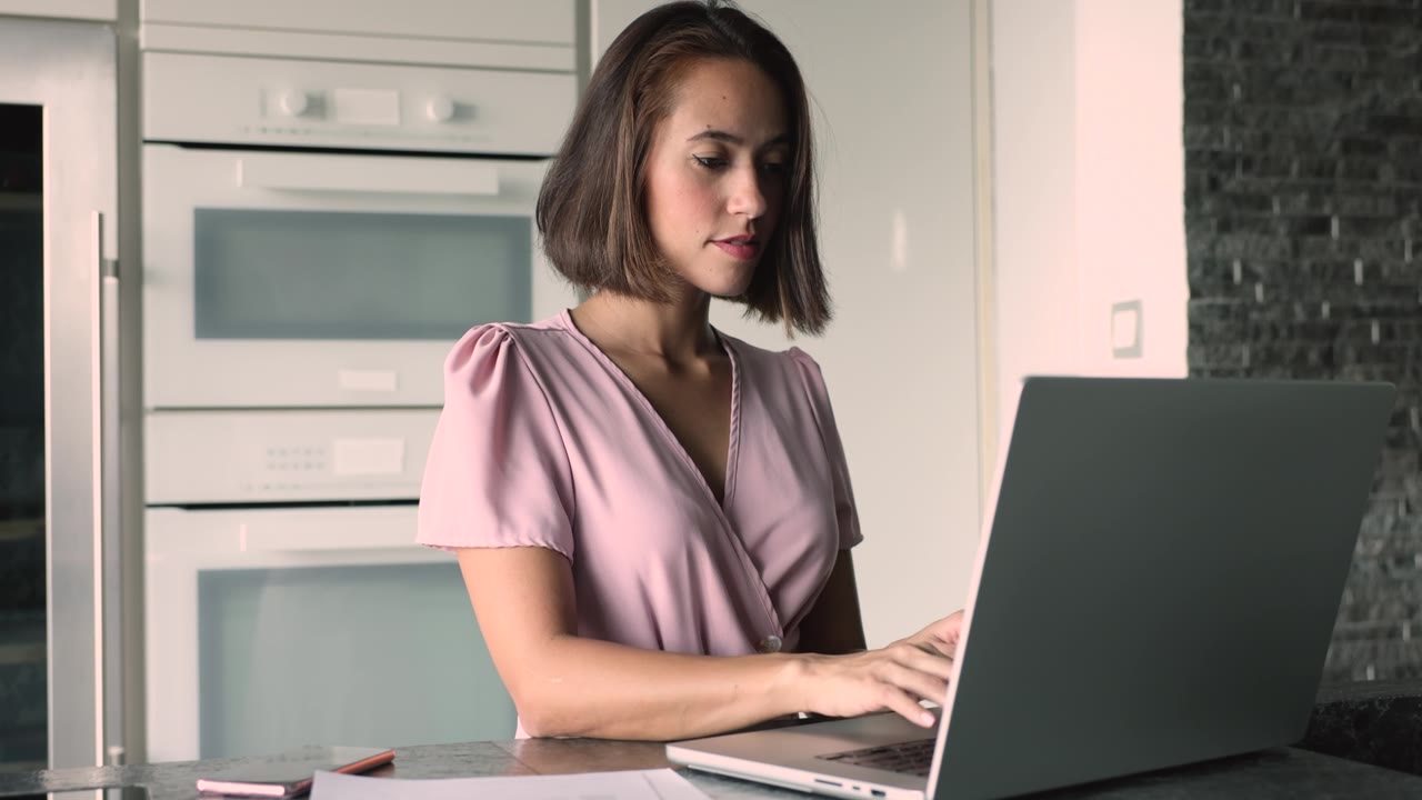 詳情圖-使用筆記本電腦在家庭廚房工作或?qū)W習(xí)的女性