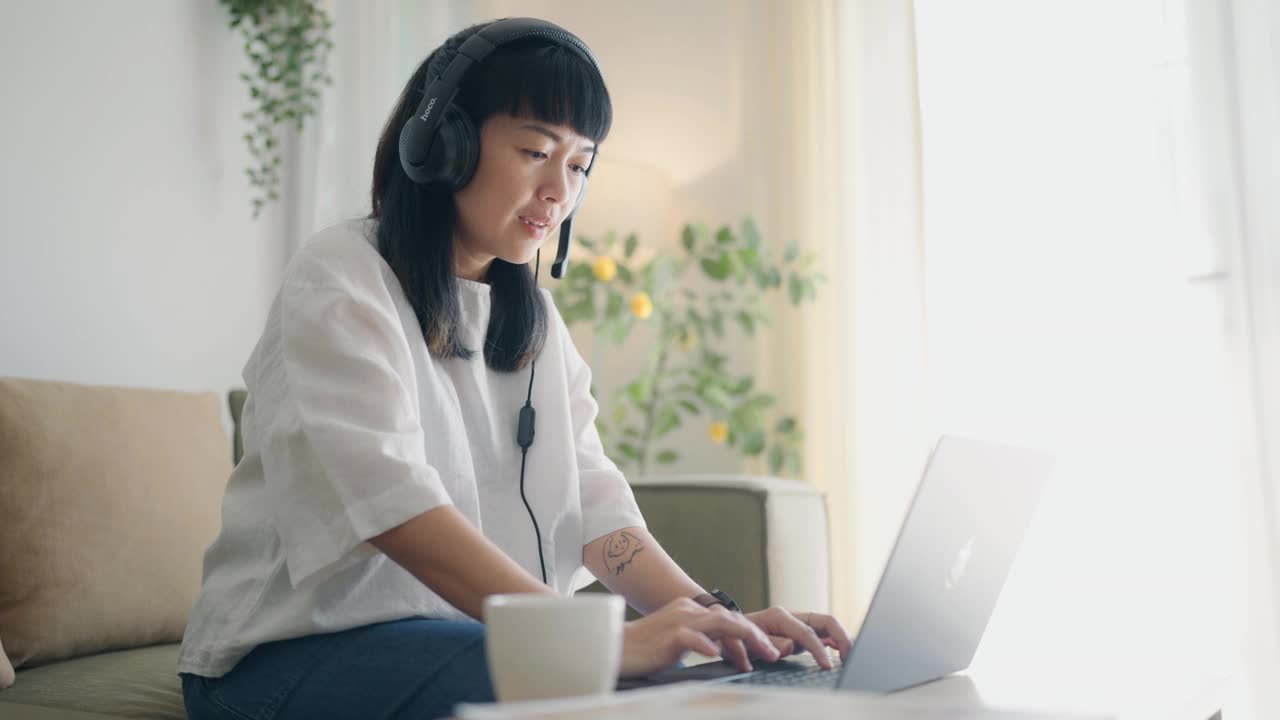 一个女人在家里的客厅里开在线会议，她在会议期间喝咖啡。