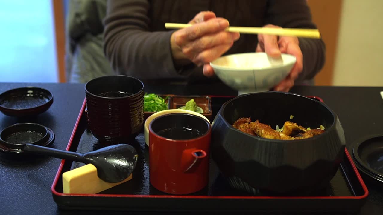老妇人正在吃Unagi Hitsumabushi烤鳗鱼饭碗
