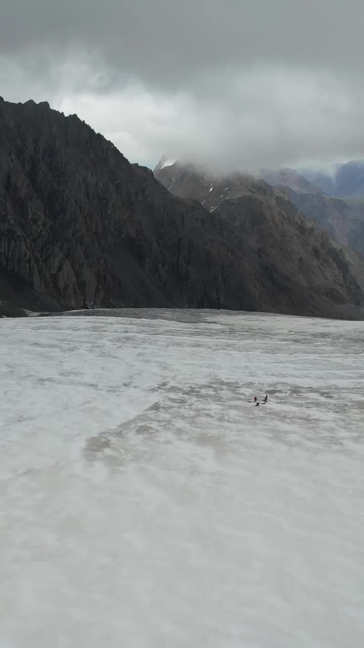 登山者在冰川上行走。无人机的垂直视频。